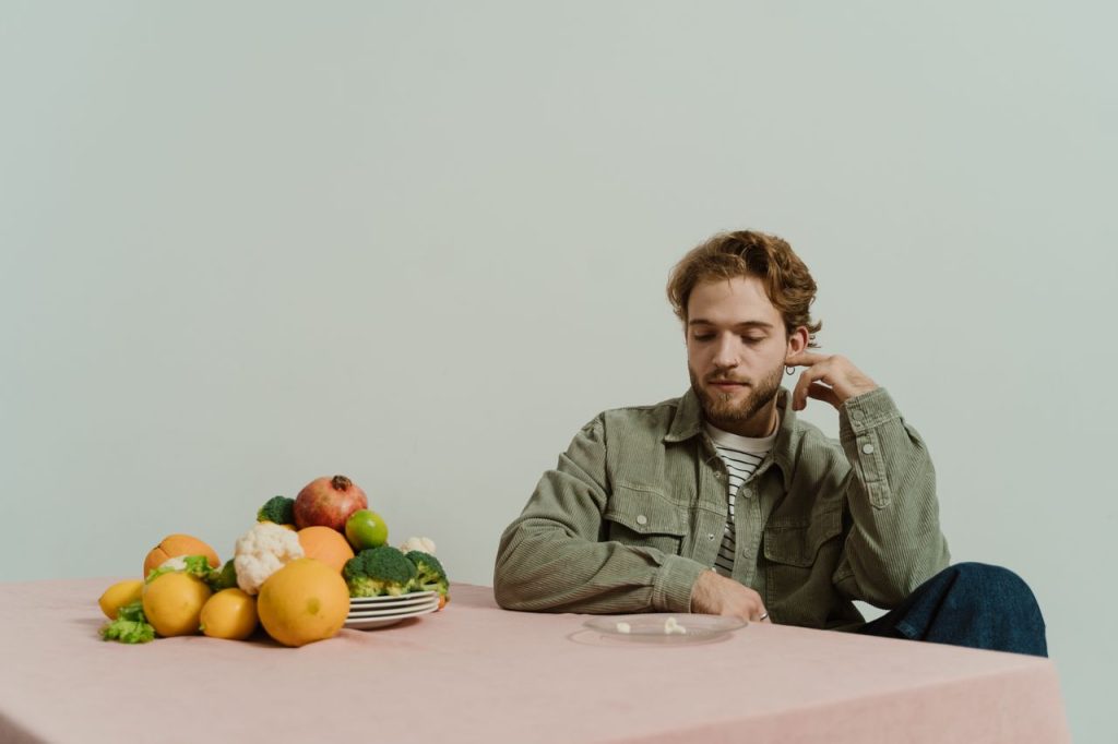 Man sitting at a table with vegetables while considering healthy food choices