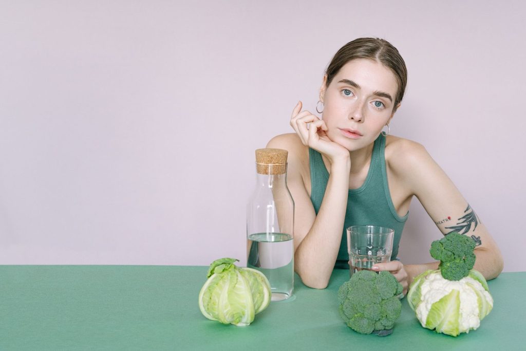 Young woman with vegetables and a glass of water representing healthy hydration and nutrition