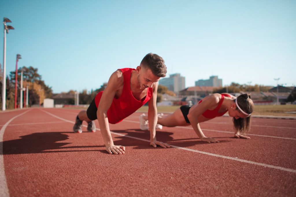Two athletes doing push-ups on a track during an outdoor workout