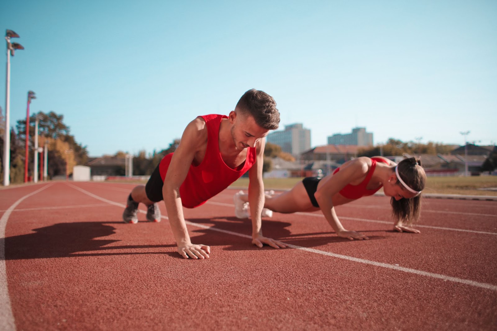 Two athletes doing push-ups on a track during an outdoor workout