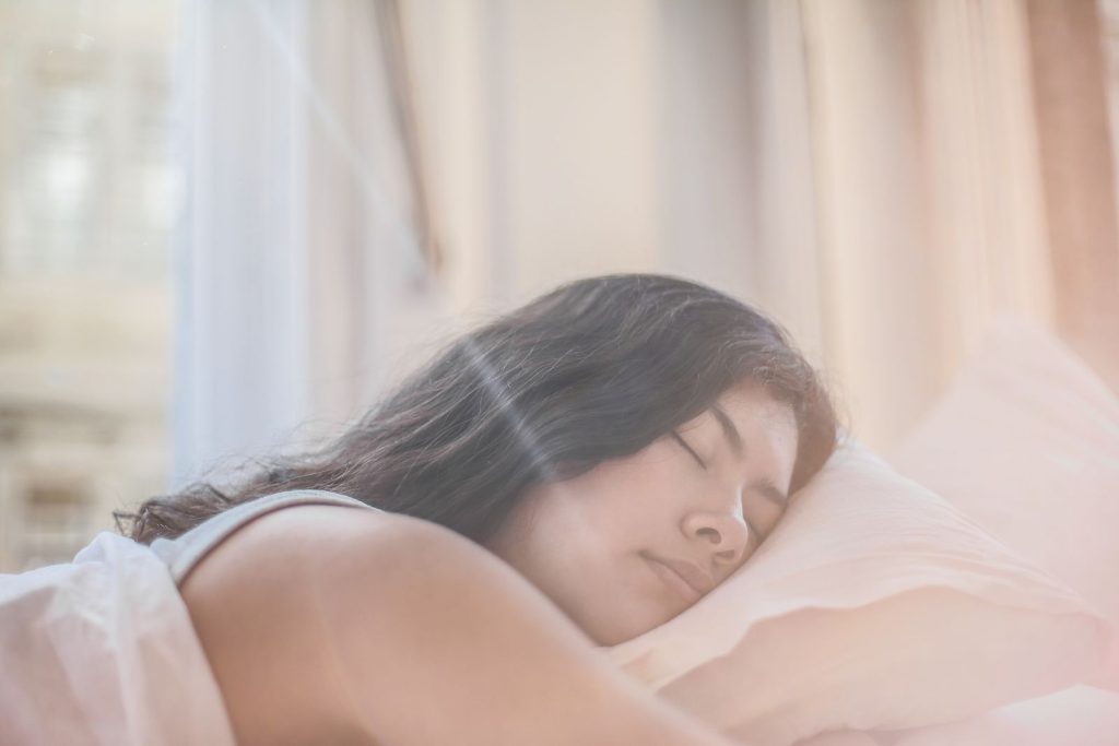 Woman sleeping peacefully in bed while practicing healthy sleep and stress management habits.
