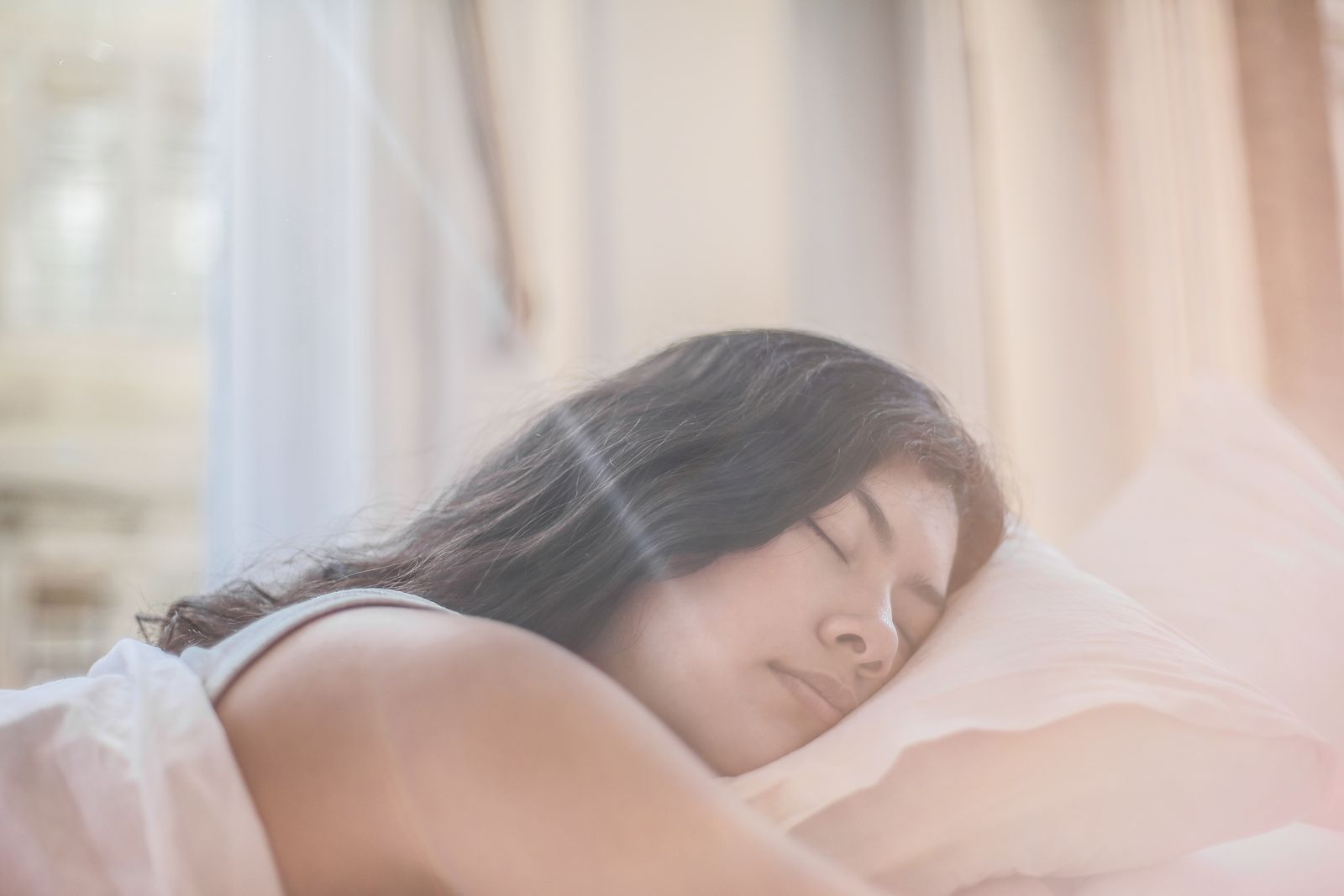 Woman sleeping peacefully in bed while practicing healthy sleep and stress management habits.