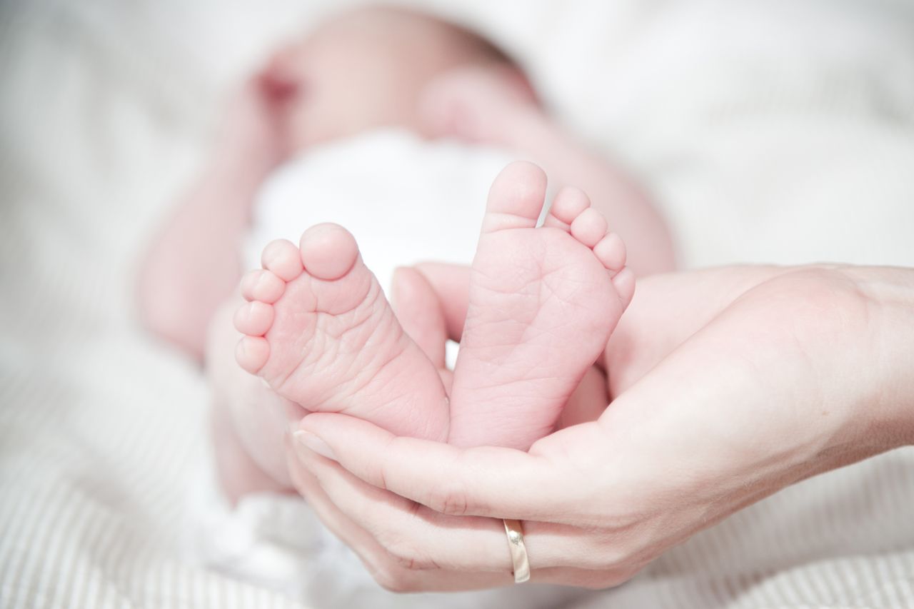 Mother gently holding her newborn baby's feet during the early postpartum period