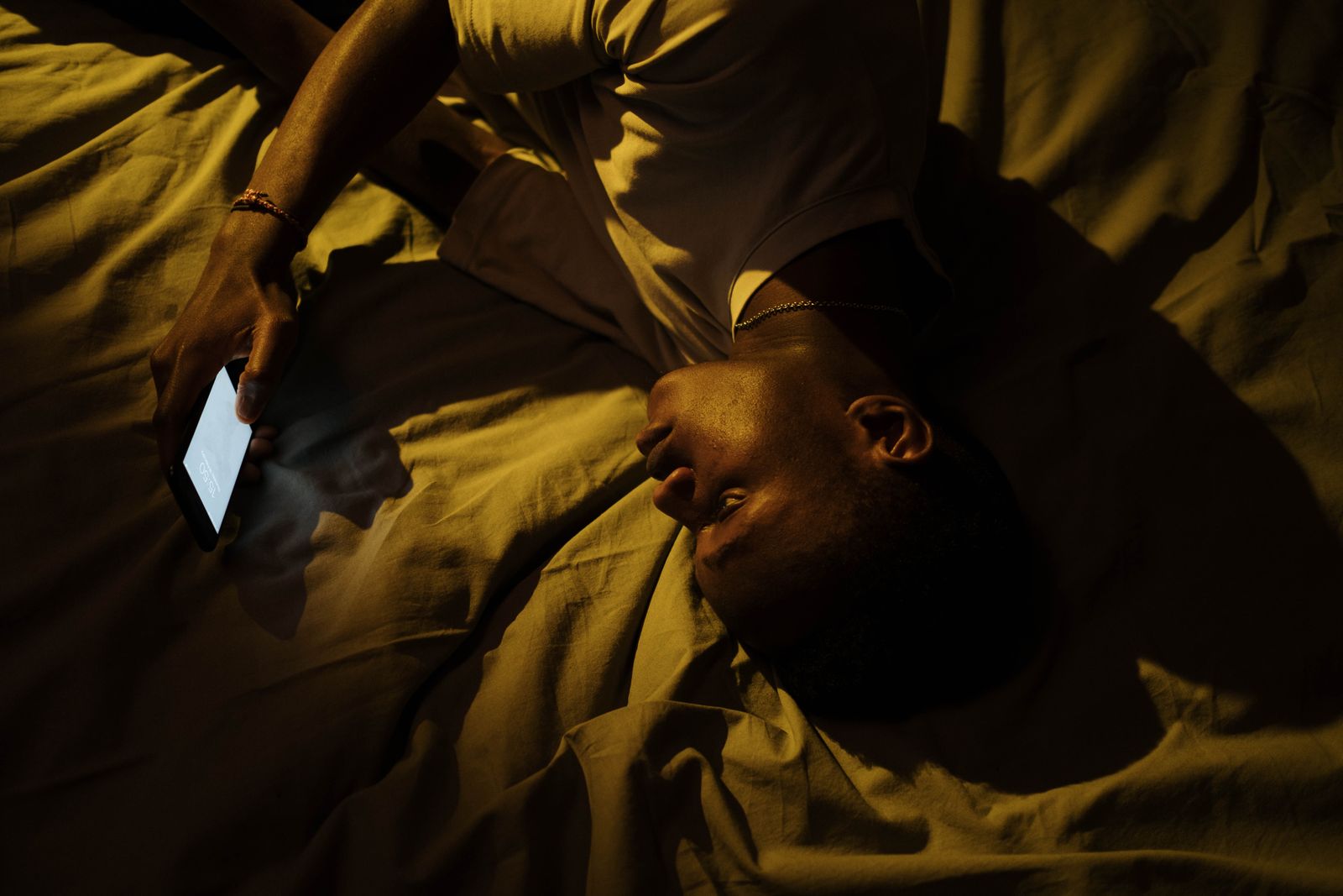 Adult man using a smartphone in bed late at night